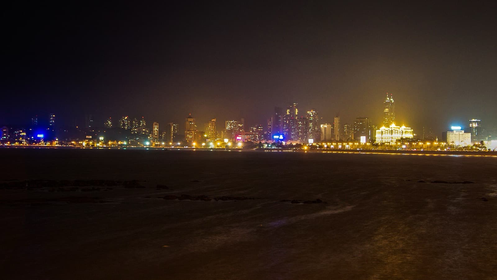 Mumbai skyline lit up at night seen across the water from Marine Drive