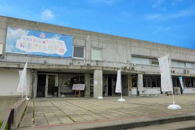 Concrete two-story building with a large banner and white flags at its entrance