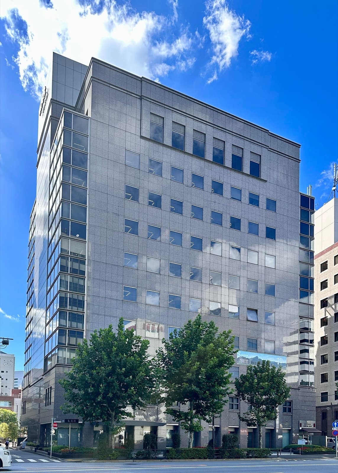 Grey stone office tower of publisher Shueisha under a blue sky in Tokyo