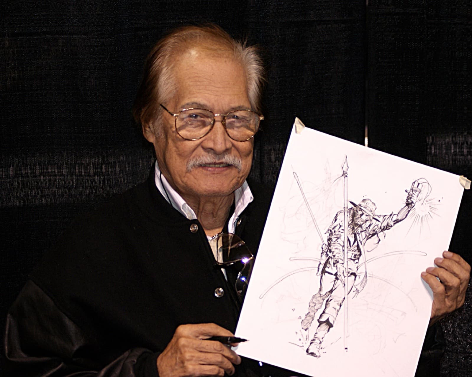 Tony DeZuniga smiling and holding up a pen and ink drawing of Jonah Hex
