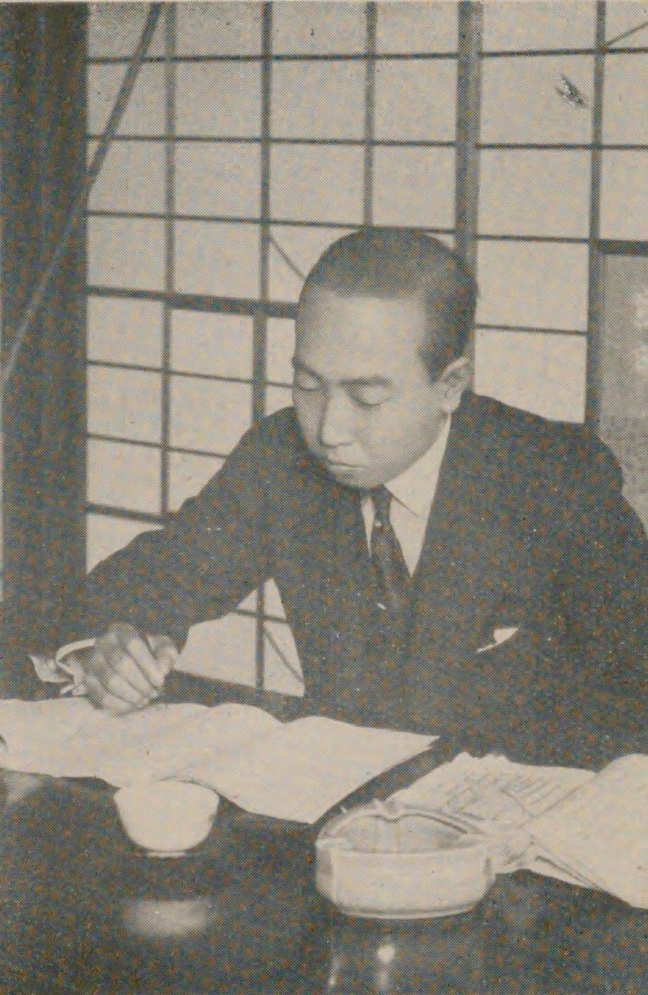 Black and white photo of Edogawa Ranpo writing at a desk