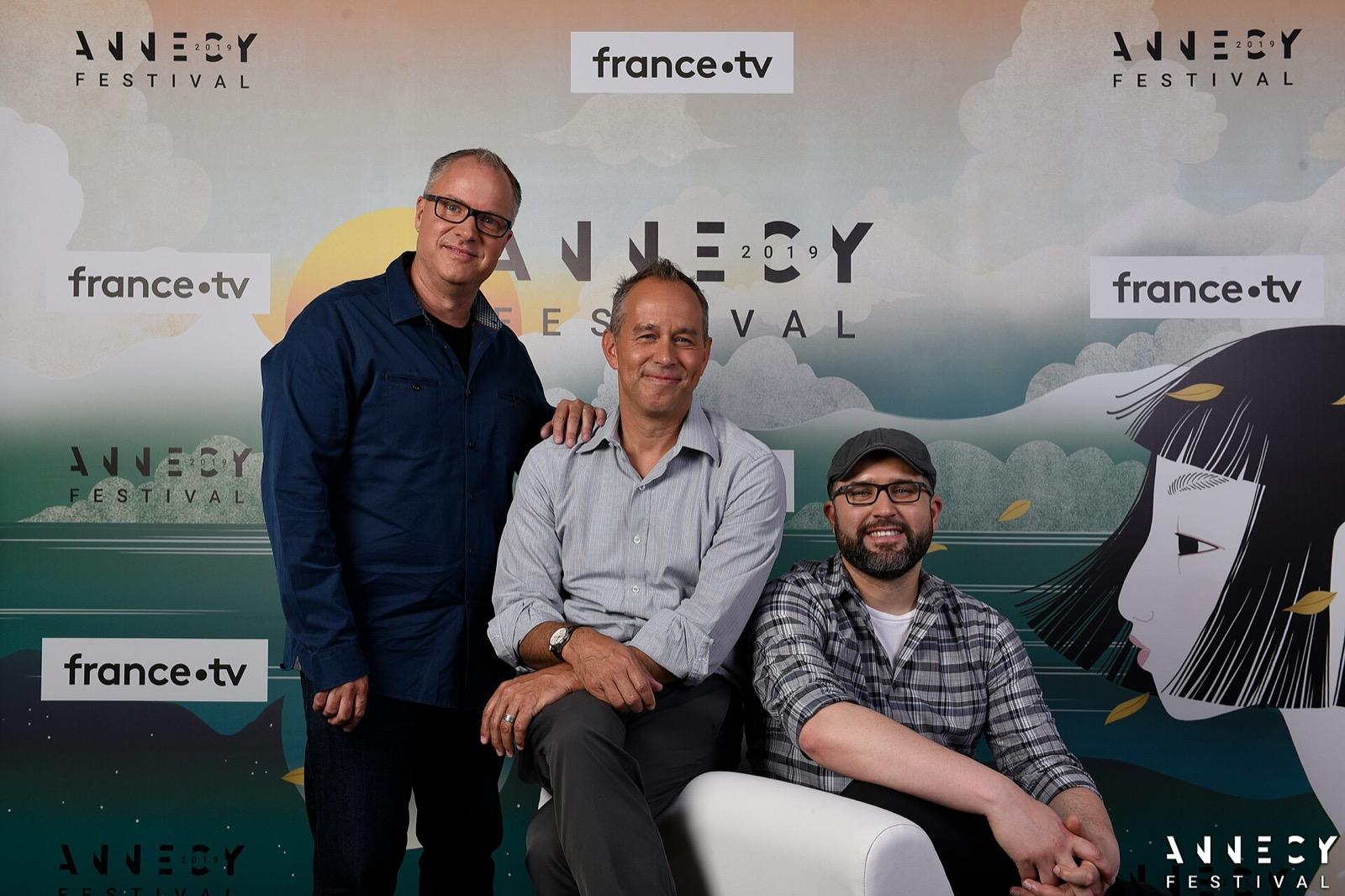 Three filmmakers posing in front of an Annecy Festival 2019 press wall