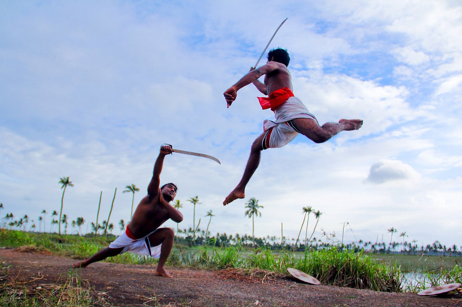 Two Kalaripayattu fighters in mock combat outdoors in rural Kerala