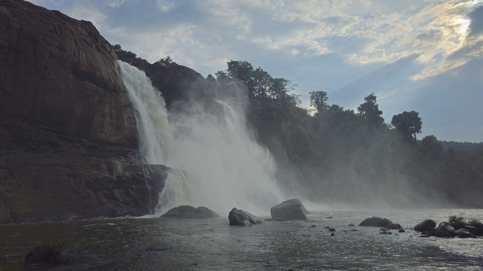 Wide waterfall cascading over rocks surrounded by green forest