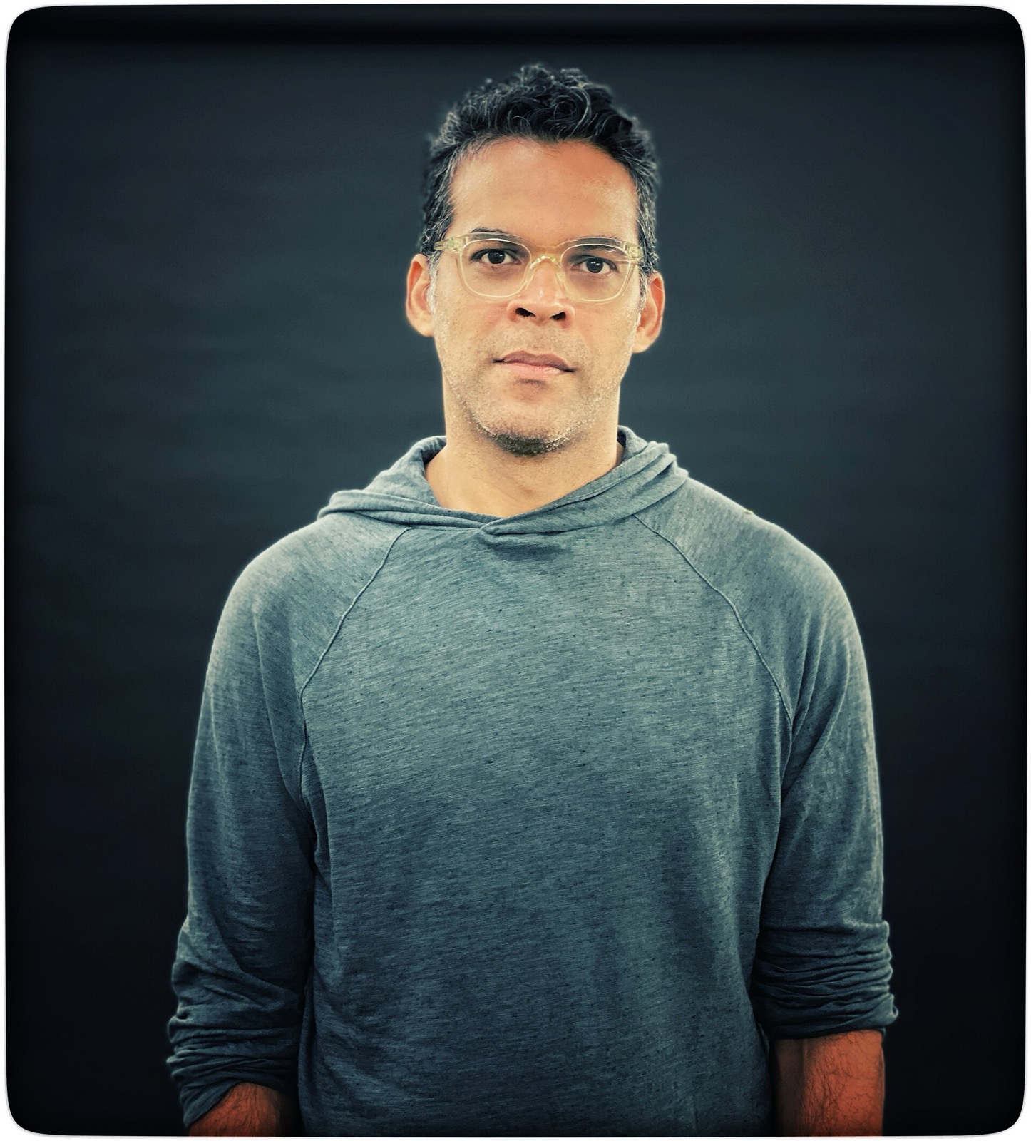 Vikramaditya Motwane in glasses and a grey hoodie against a dark backdrop