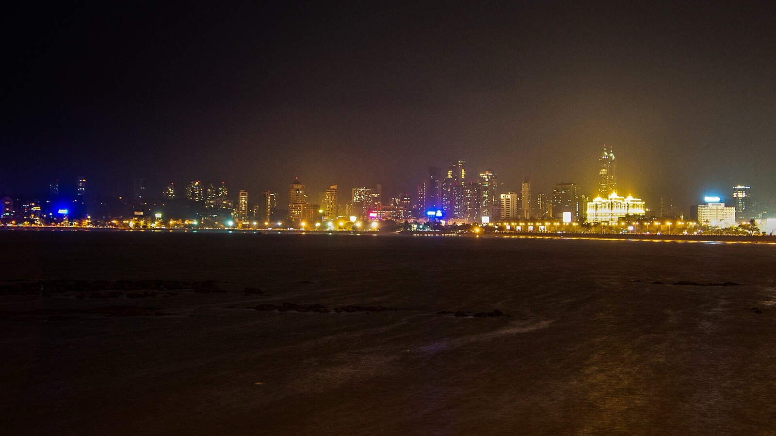 Mumbai skyline lit up at night seen across the water from Marine Drive