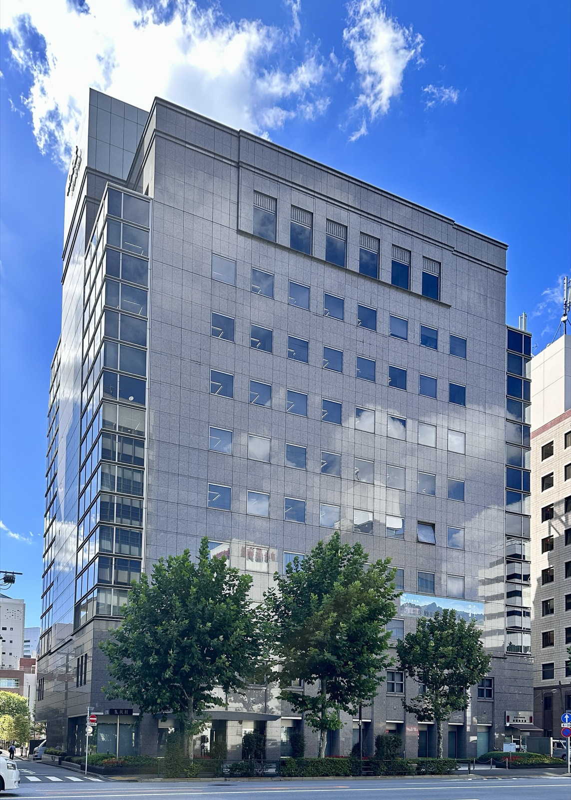 Grey stone office tower of publisher Shueisha under a blue sky in Tokyo