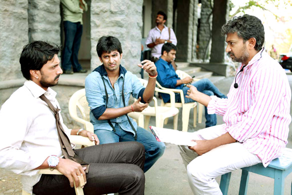 Actors Sudeep and Nani sitting in chairs talking on the Eega film set