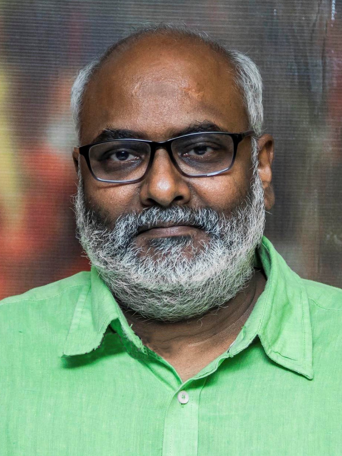 Portrait of composer M. M. Keeravani wearing glasses and a green shirt