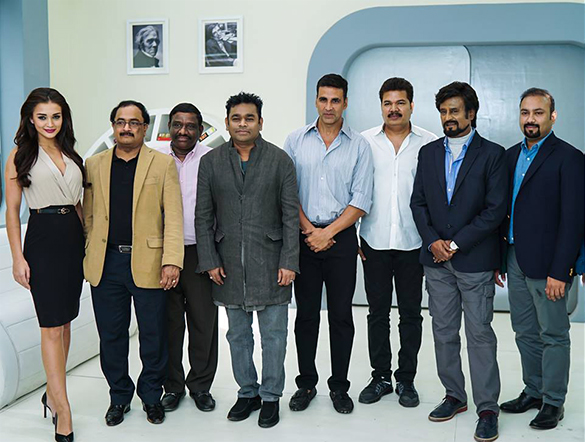 Cast and crew of 2.0 standing in a row on a white futuristic film set