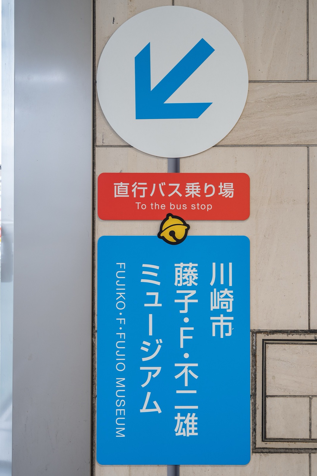 Blue Fujiko F Fujio Museum sign with an arrow pointing to the bus stop
