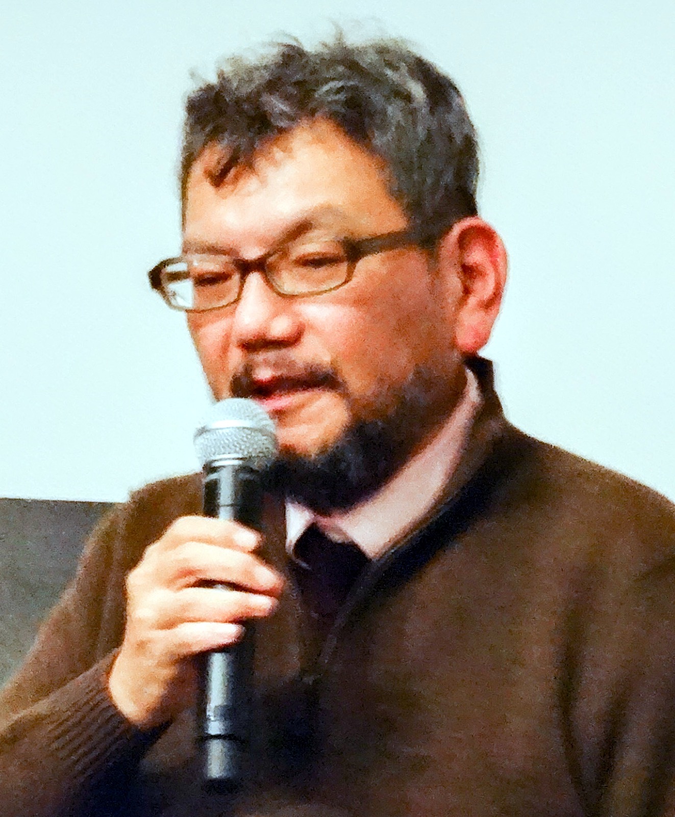 Hideaki Anno speaking into a microphone at a film festival event
