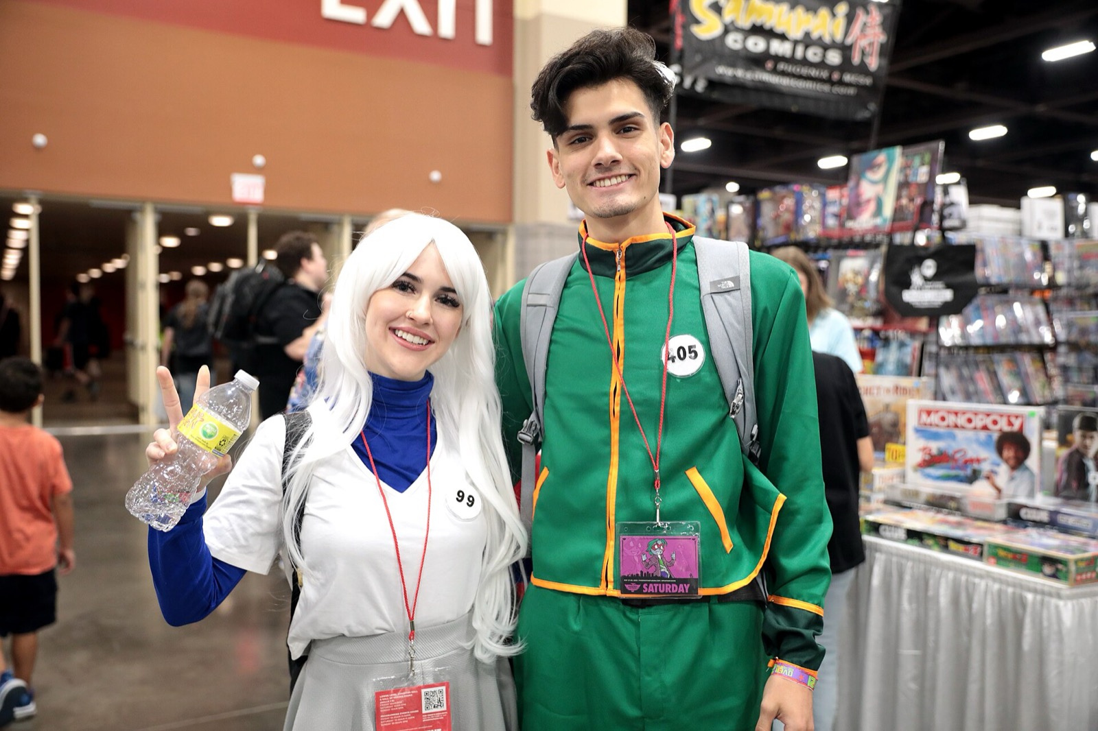 Two cosplayers in Gon's green outfit and Killua's white wig posing indoors