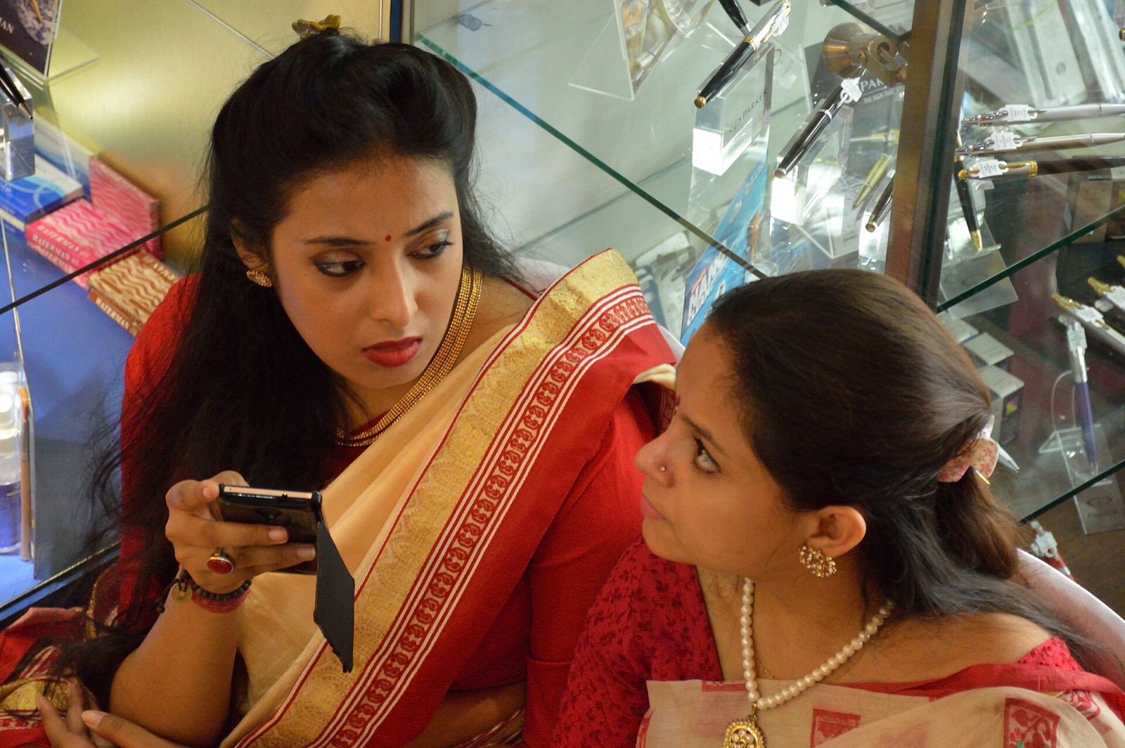 Two women in saris looking at a smartphone in Kolkata