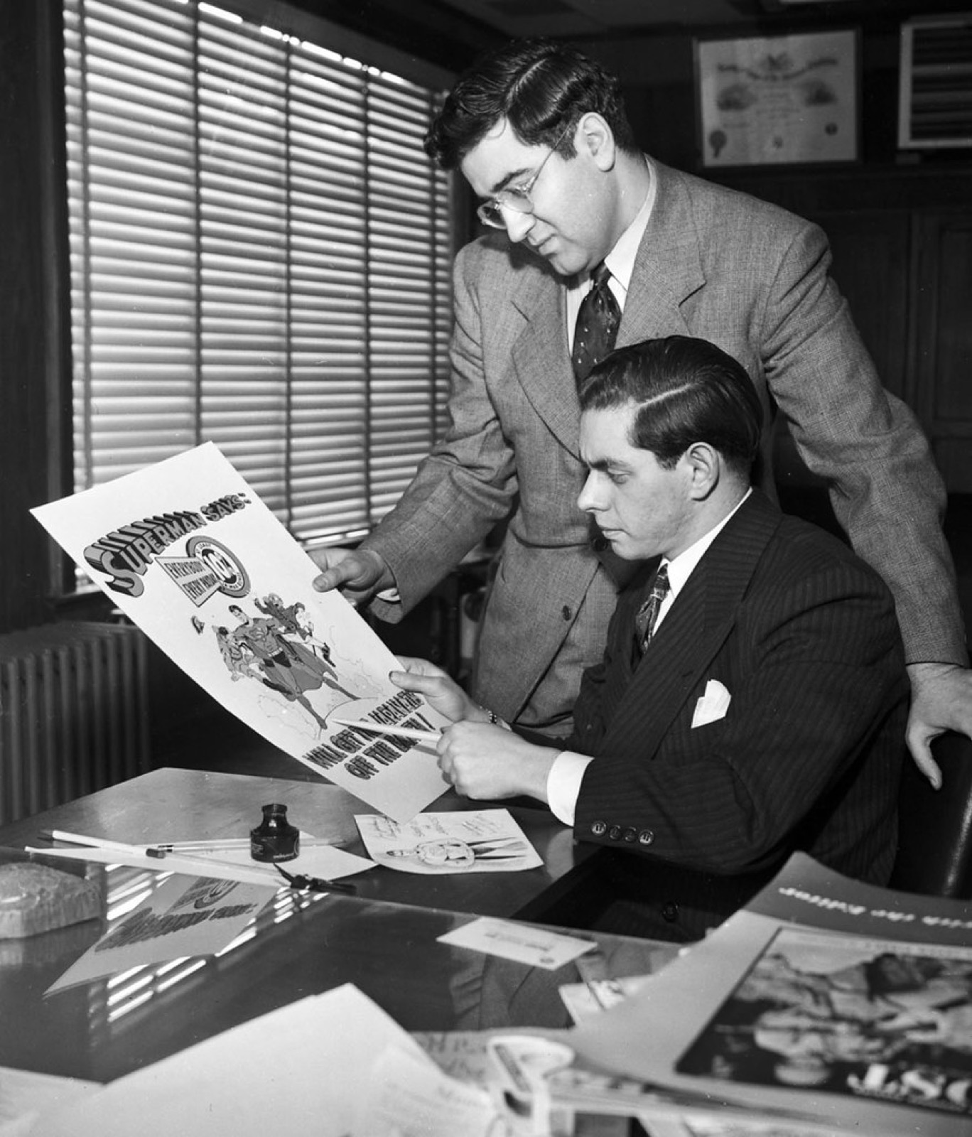 Black and white photo of Jerry Siegel and Joe Shuster at a drawing board
