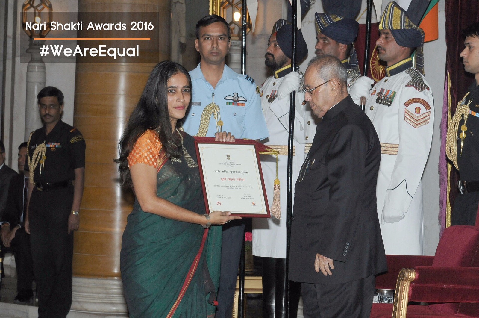 Amruta Patil in a green sari holding a framed citation beside President Pranab Mukherjee