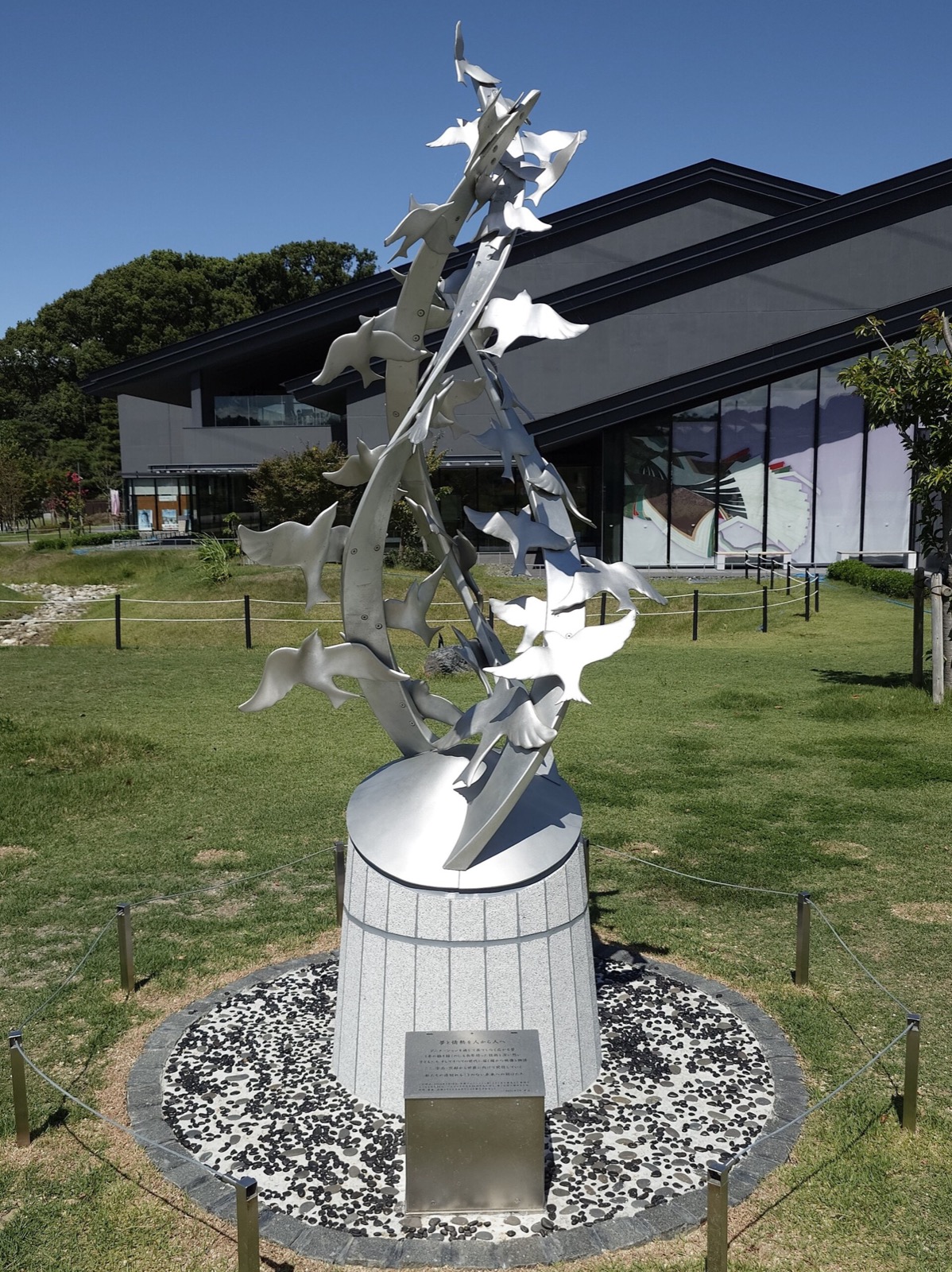 Steel sculpture of birds spiraling skyward on a stone pedestal