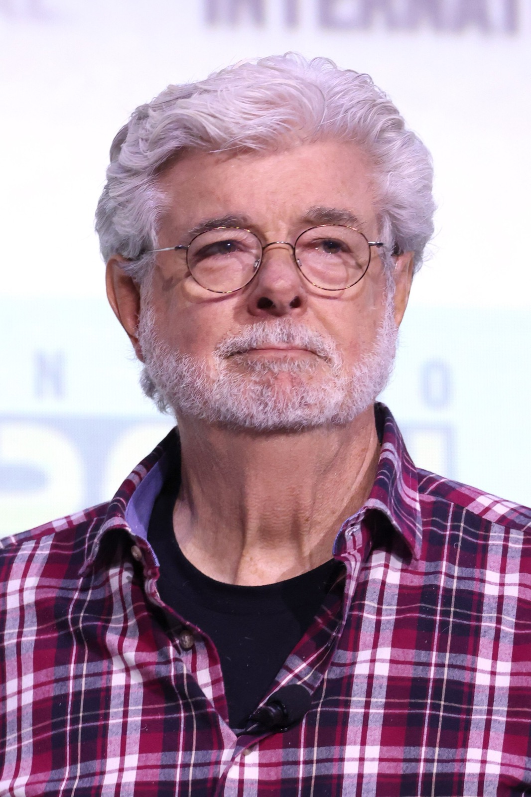 George Lucas in glasses and a plaid shirt on a convention stage