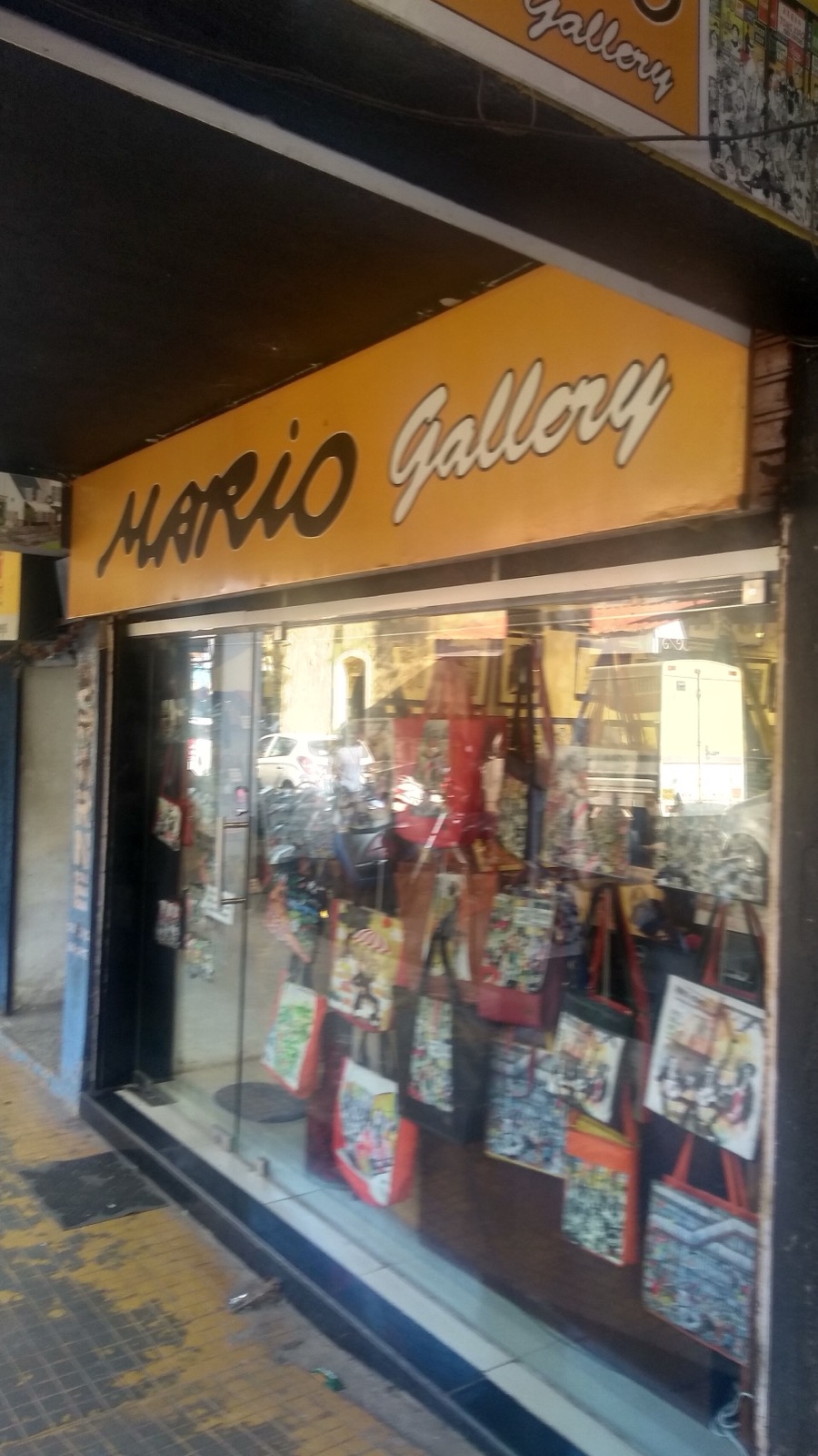 Shopfront with a yellow Mario Gallery sign and printed tote bags in the window