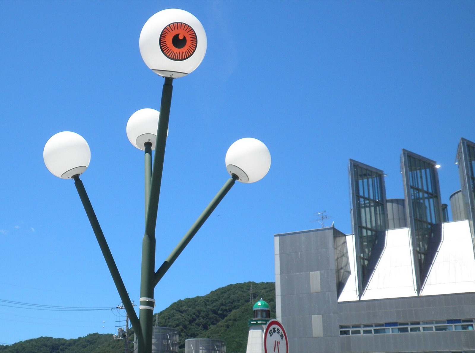 Street lamp with globes shaped like a giant eyeball against blue sky