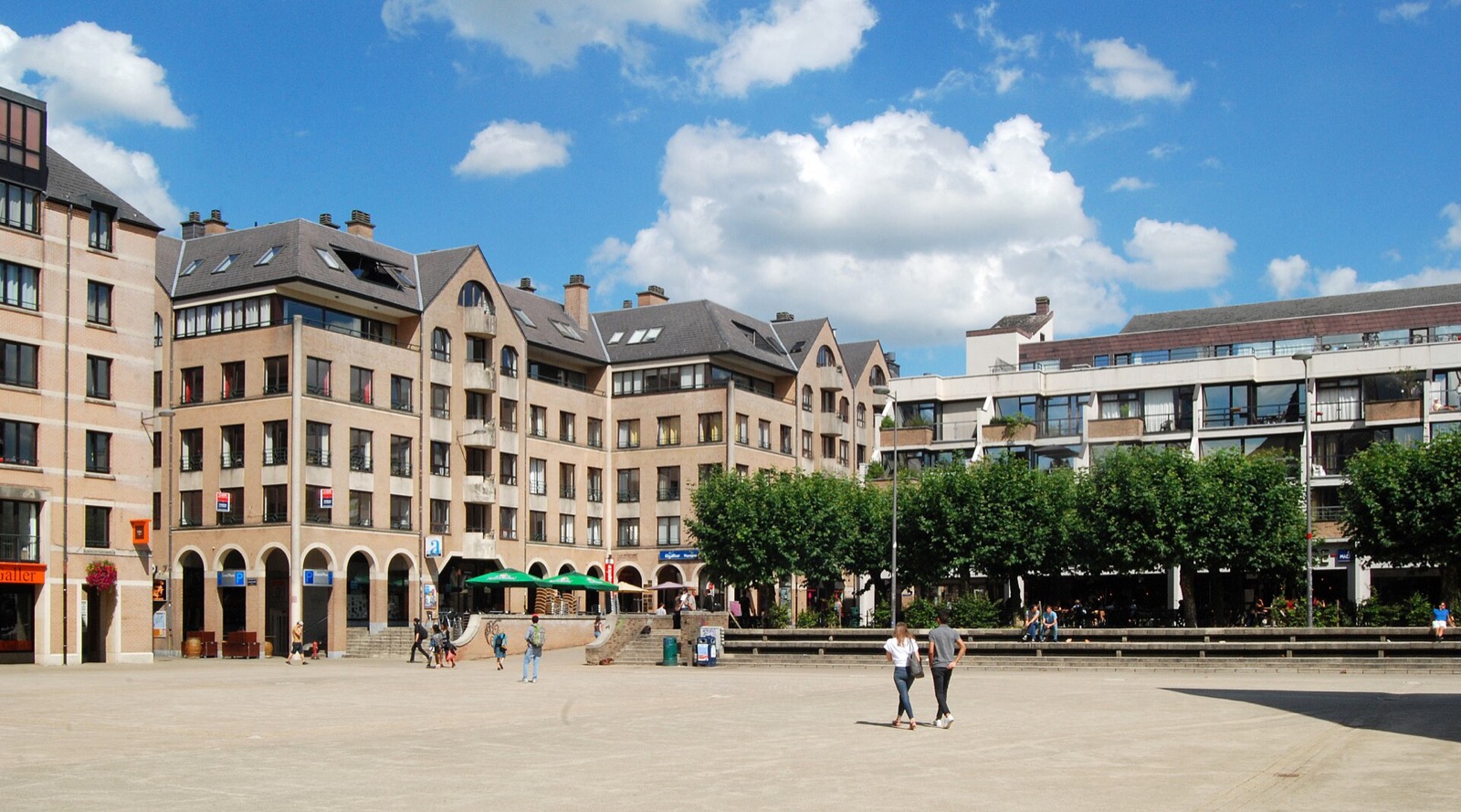 Sunny pedestrian square ringed by brick buildings and rows of trees
