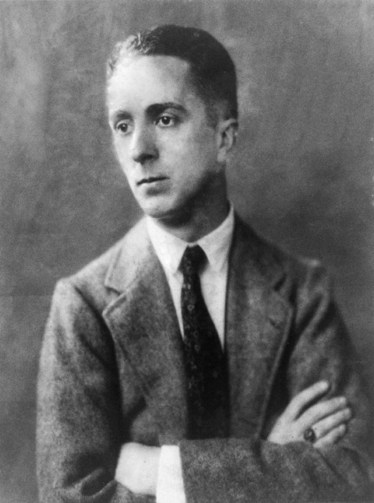 Black and white portrait of a young Norman Rockwell in a suit with folded arms