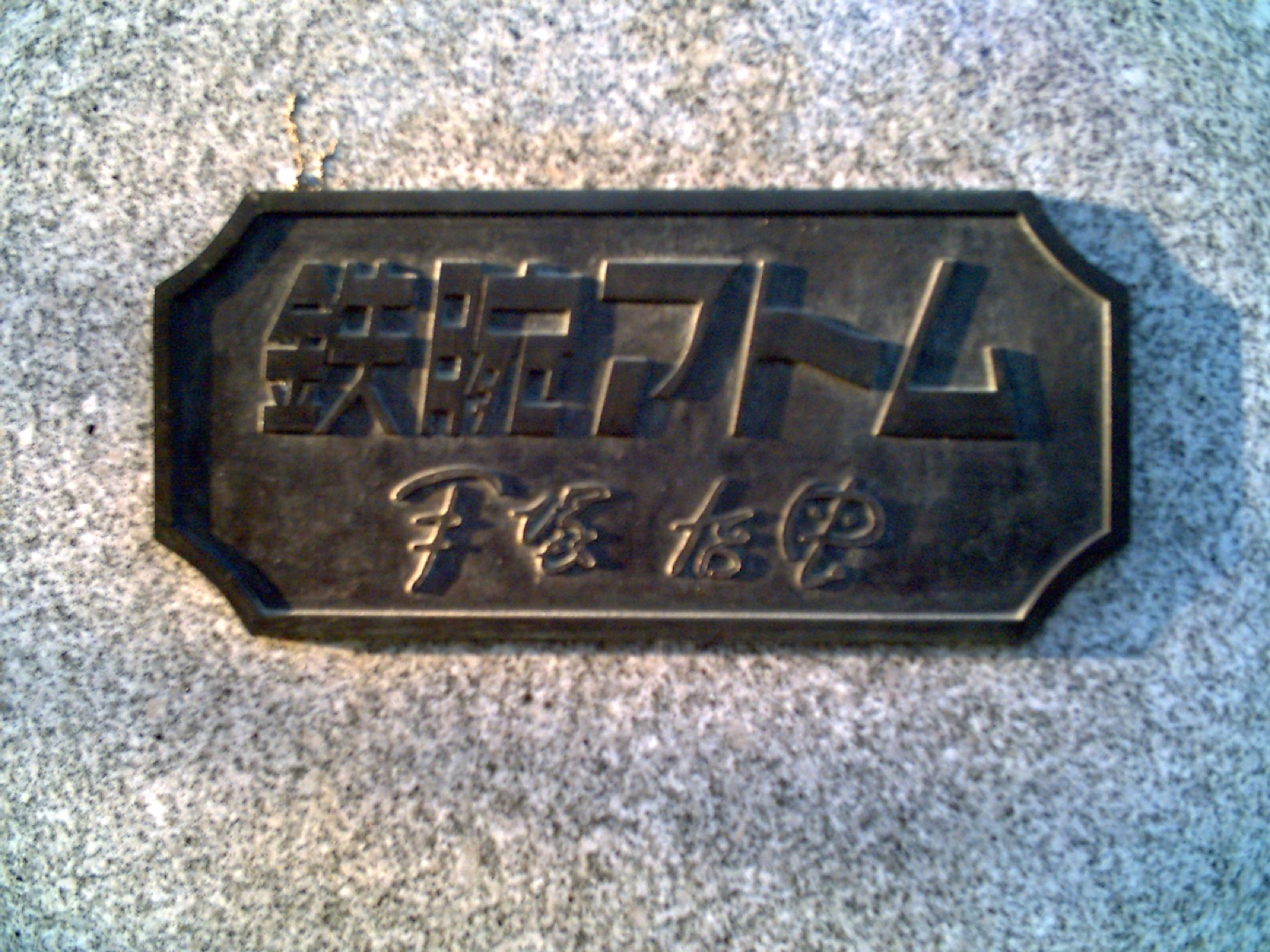 Bronze plaque engraved with Tetsuwan Atom lettering and Osamu Tezuka's signature set in granite