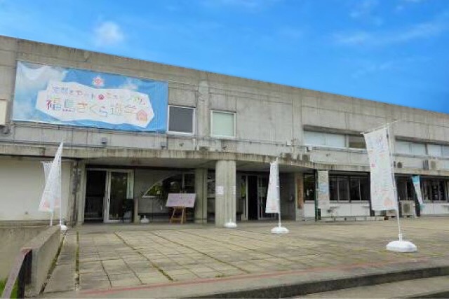 Concrete two-story building with a large banner and white flags at its entrance