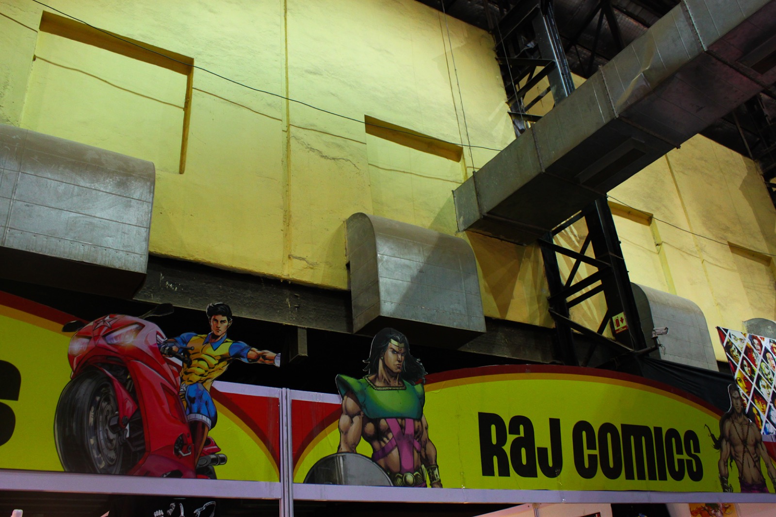 Convention stall banner reading Raj Comics with superhero character artwork