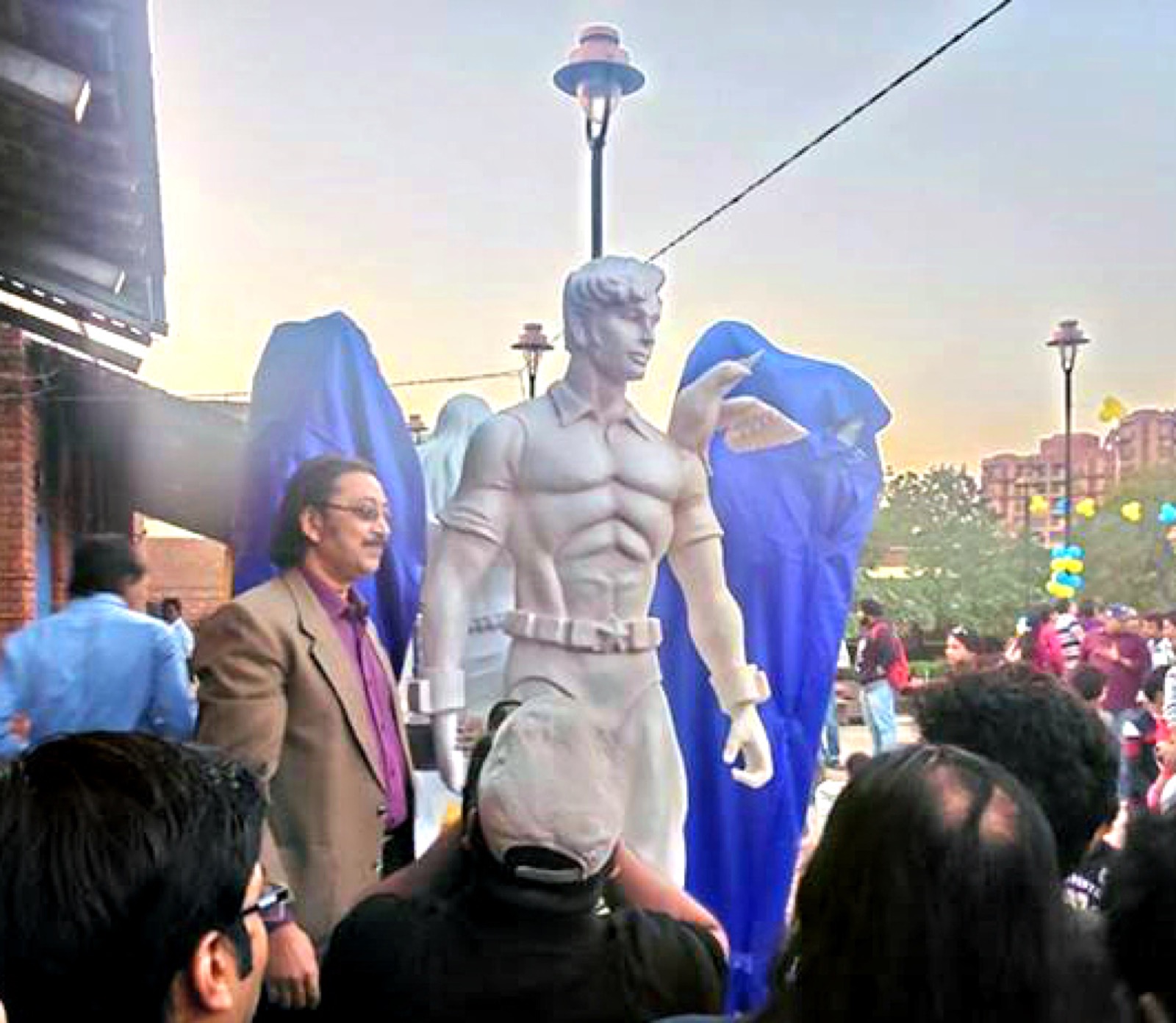 Anupam Sinha standing beside a white statue of Super Commando Dhruva outdoors