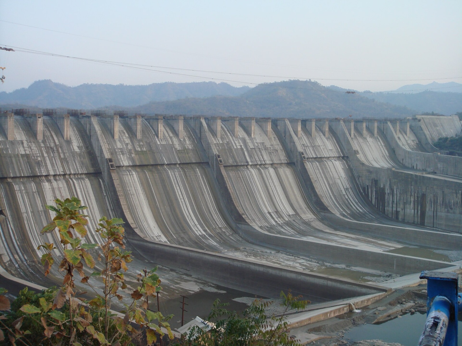 The concrete spillway of the Sardar Sarovar Dam with hills behind it