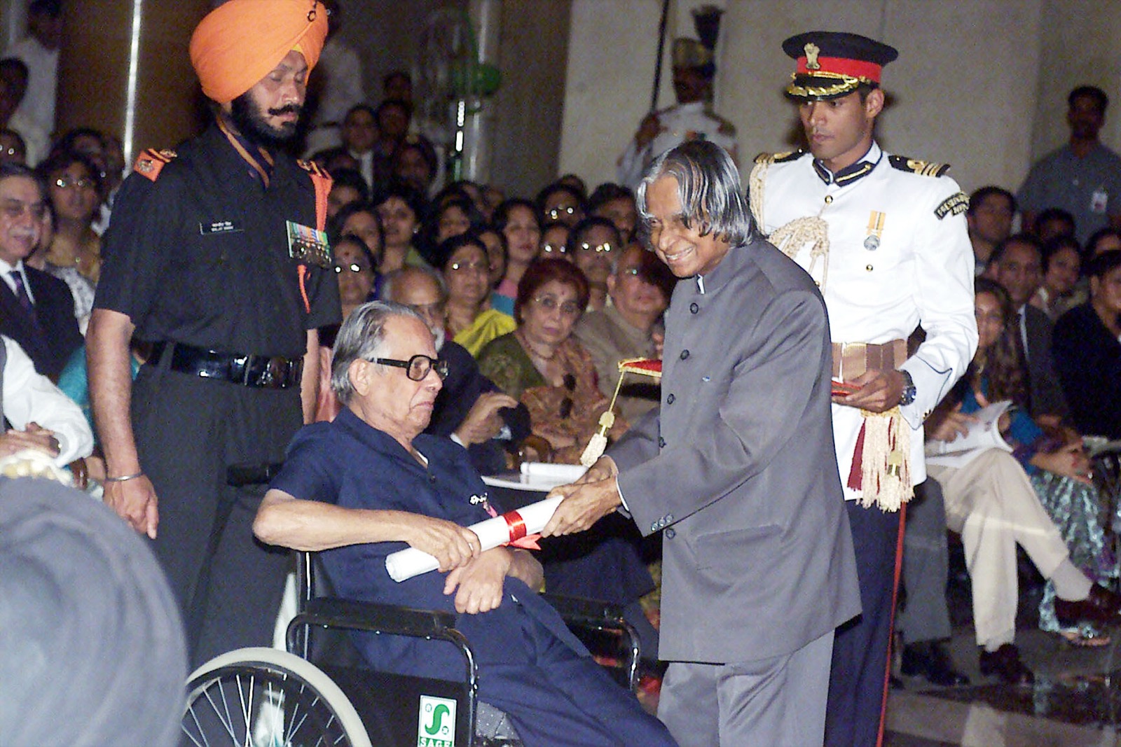 R. K. Laxman in a wheelchair accepting an award scroll from President Kalam at a ceremony