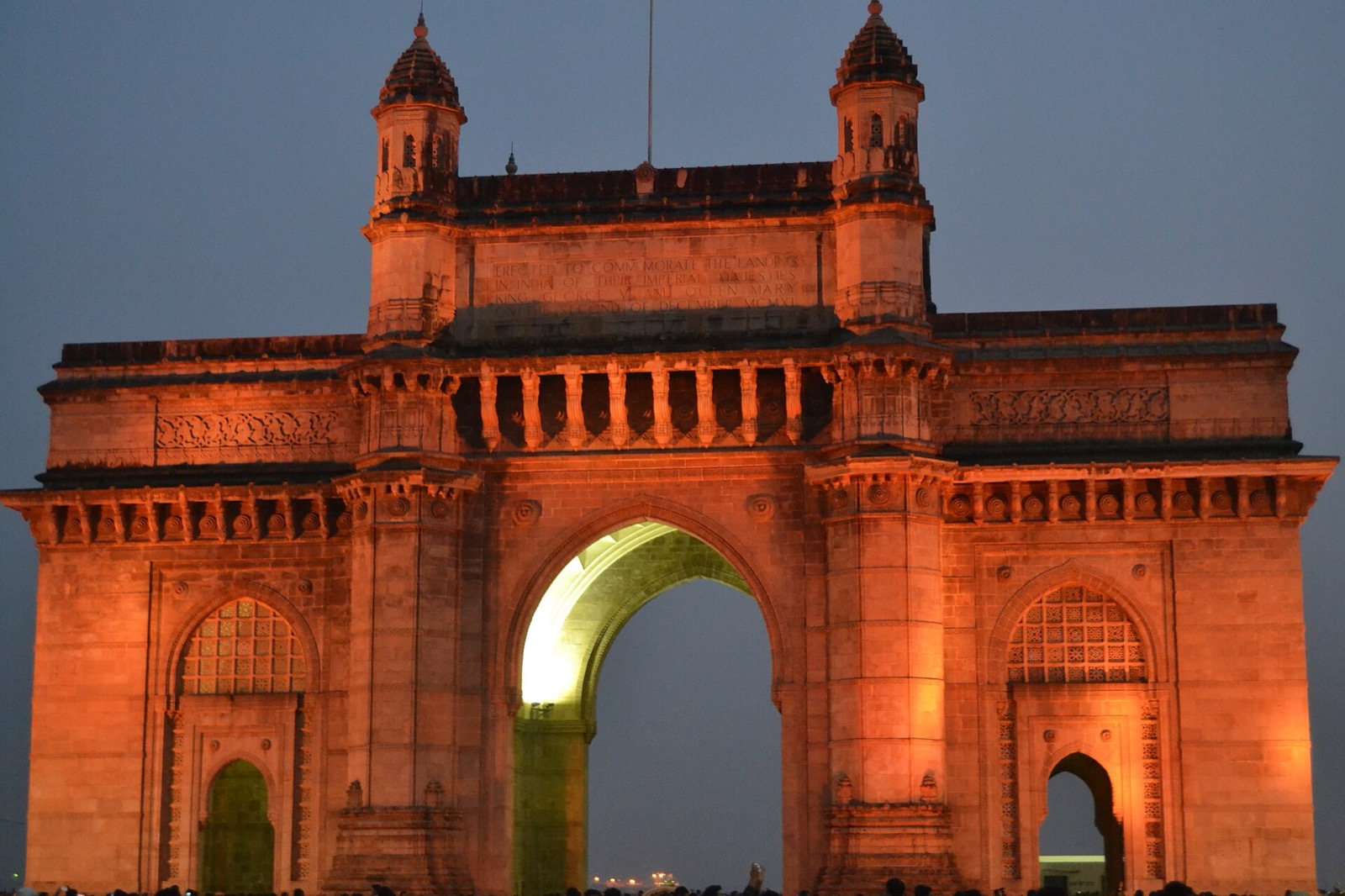 The Gateway of India monument lit orange against an evening sky