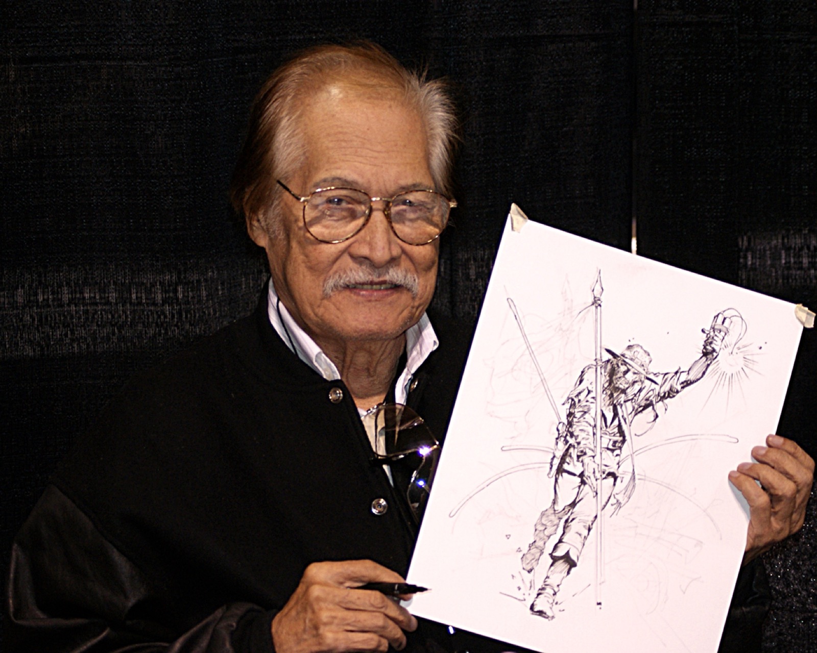 Tony DeZuniga smiling and holding up a pen and ink drawing of Jonah Hex